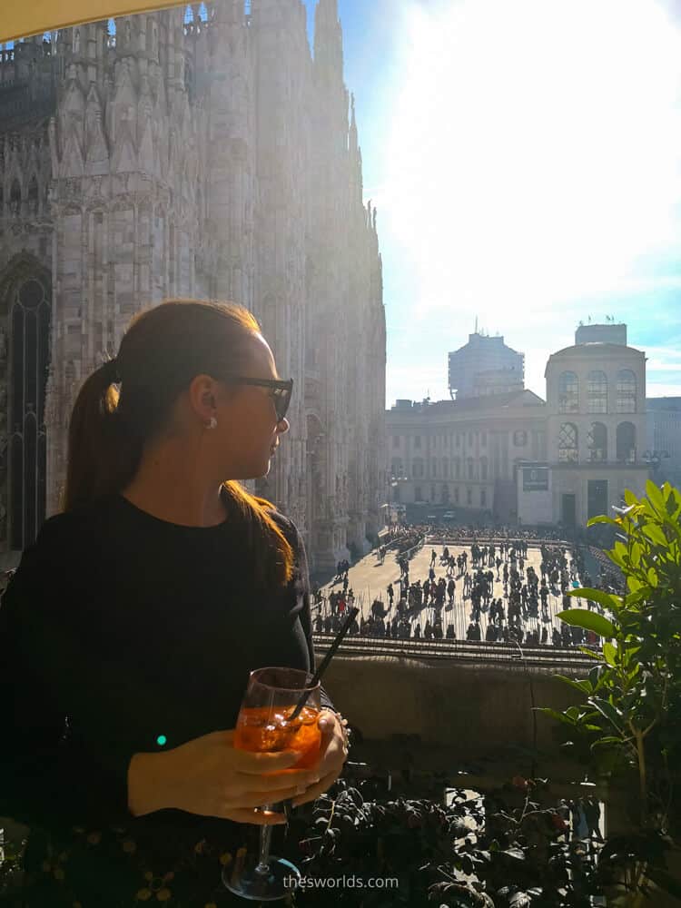 Girl looking from balcony drinking wine at people in Milan