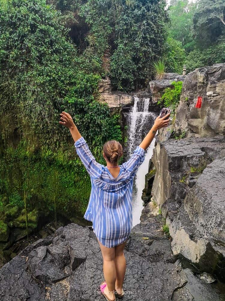 Girl standing at top of waterfall in Bali