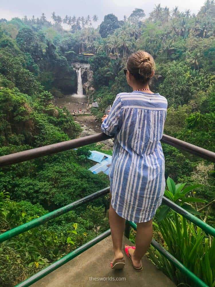 Girl standing on balcony looking at forest and waterfall