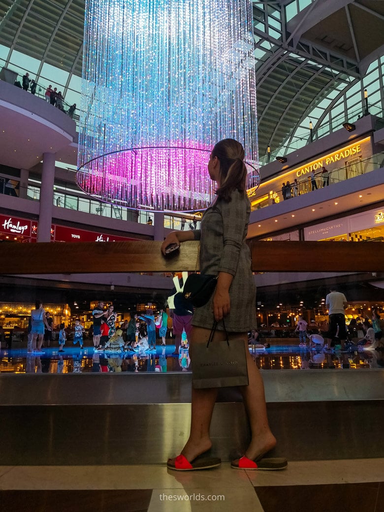 Girl looking at chandelier while people shop at Marina bay Shopping mall