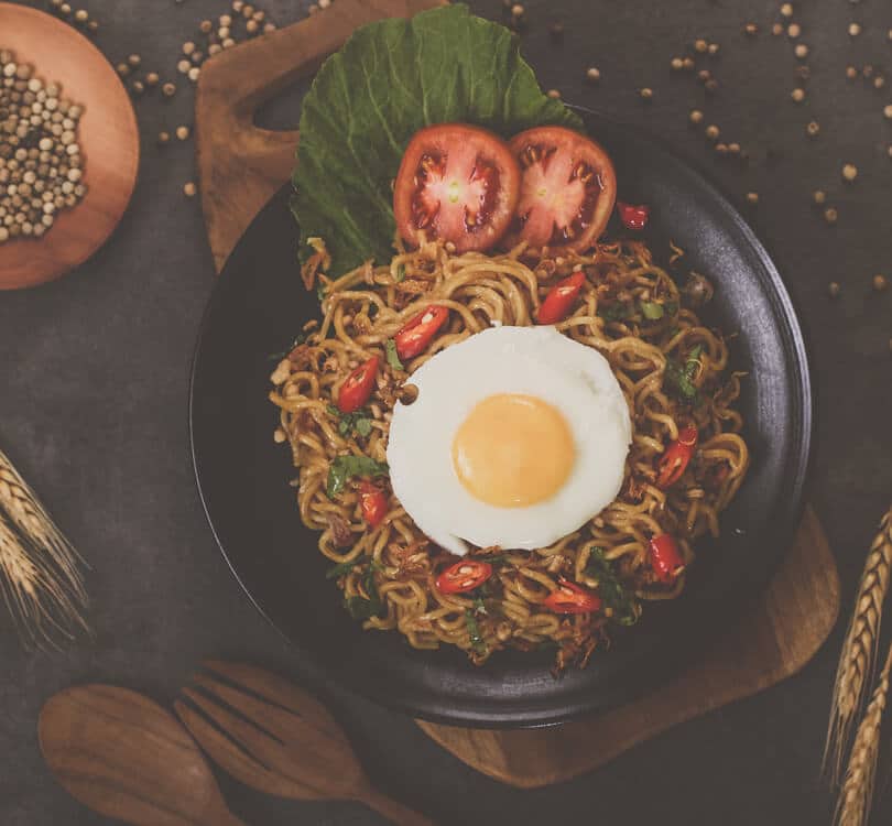 Spaghetti with egg and tomatoes on a black plate