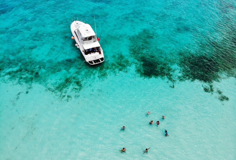 People in ocean next to boat at Cancun, Mexico