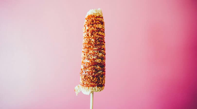 Elote on stick with pink background