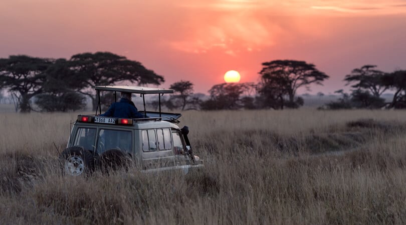 People in a jeep looking at sunset at Serengeti National park